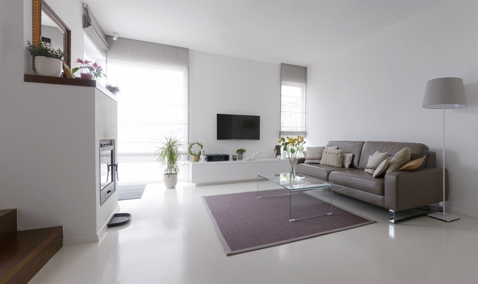 White living room with taupe leather sofa and glass table