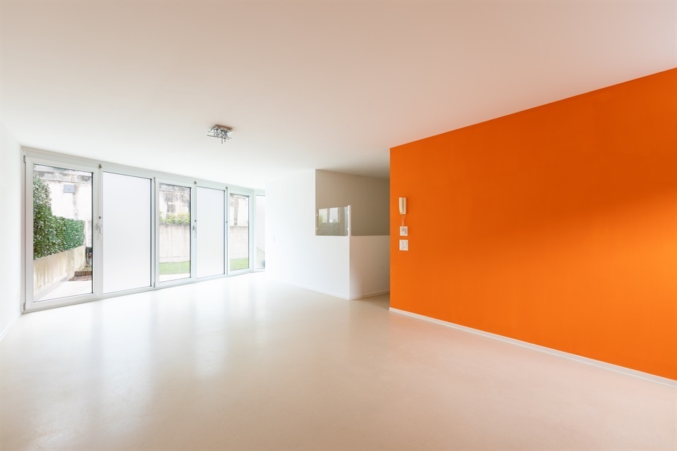 Front view of the room with white and orange walls. Resin floor. No one inside